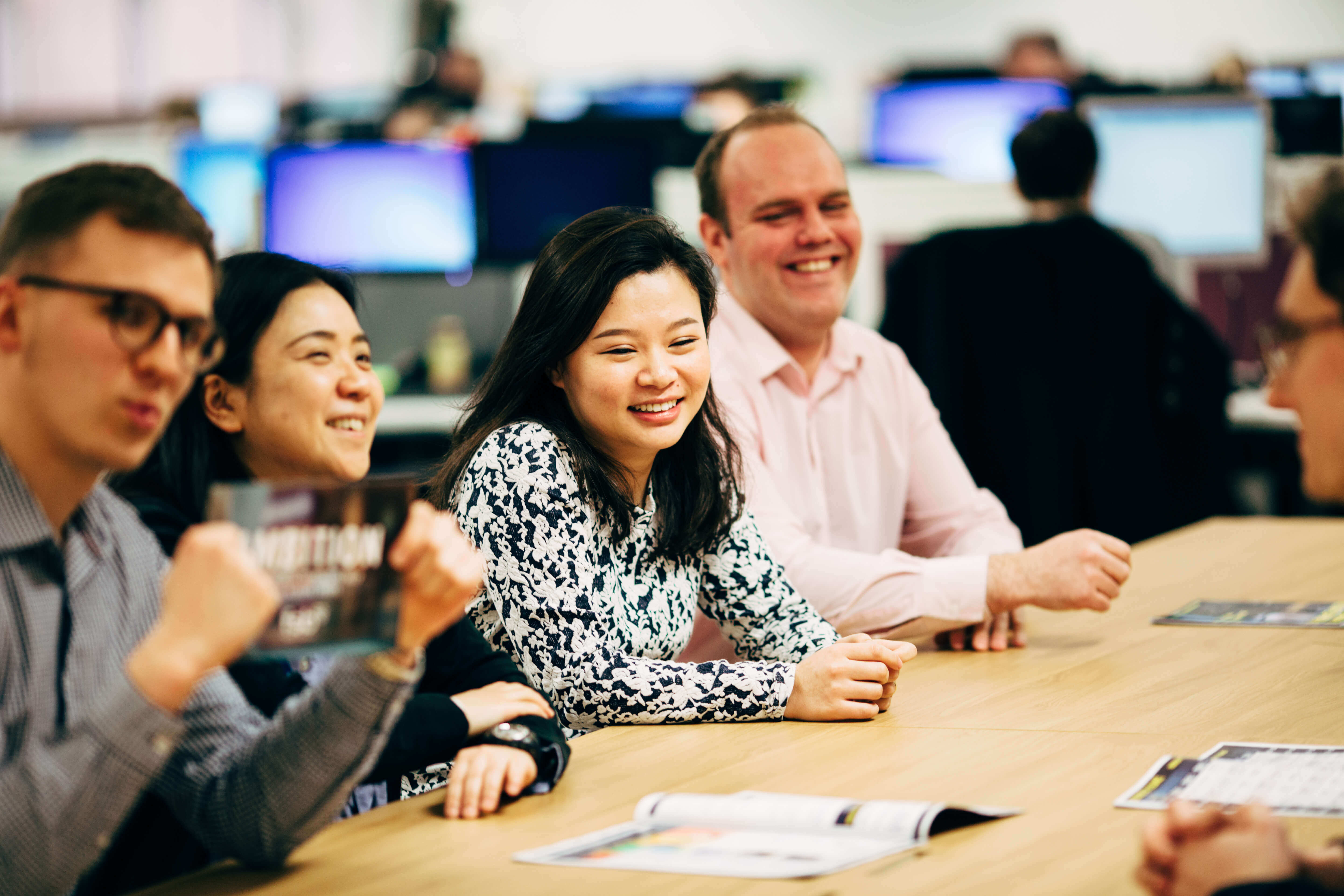 colleagues sat at a wooden table having a conversation in an office